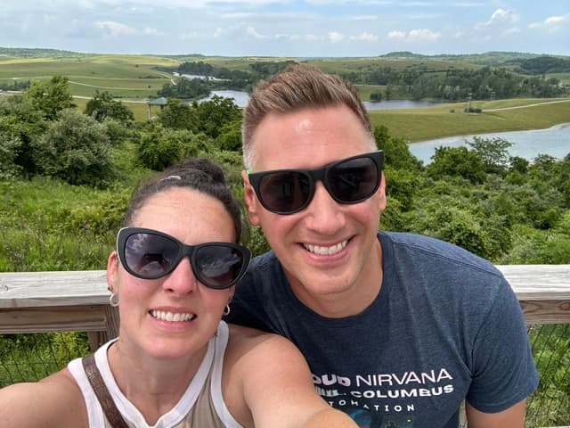 Jon and his wife overlooking a green hillside and lake
